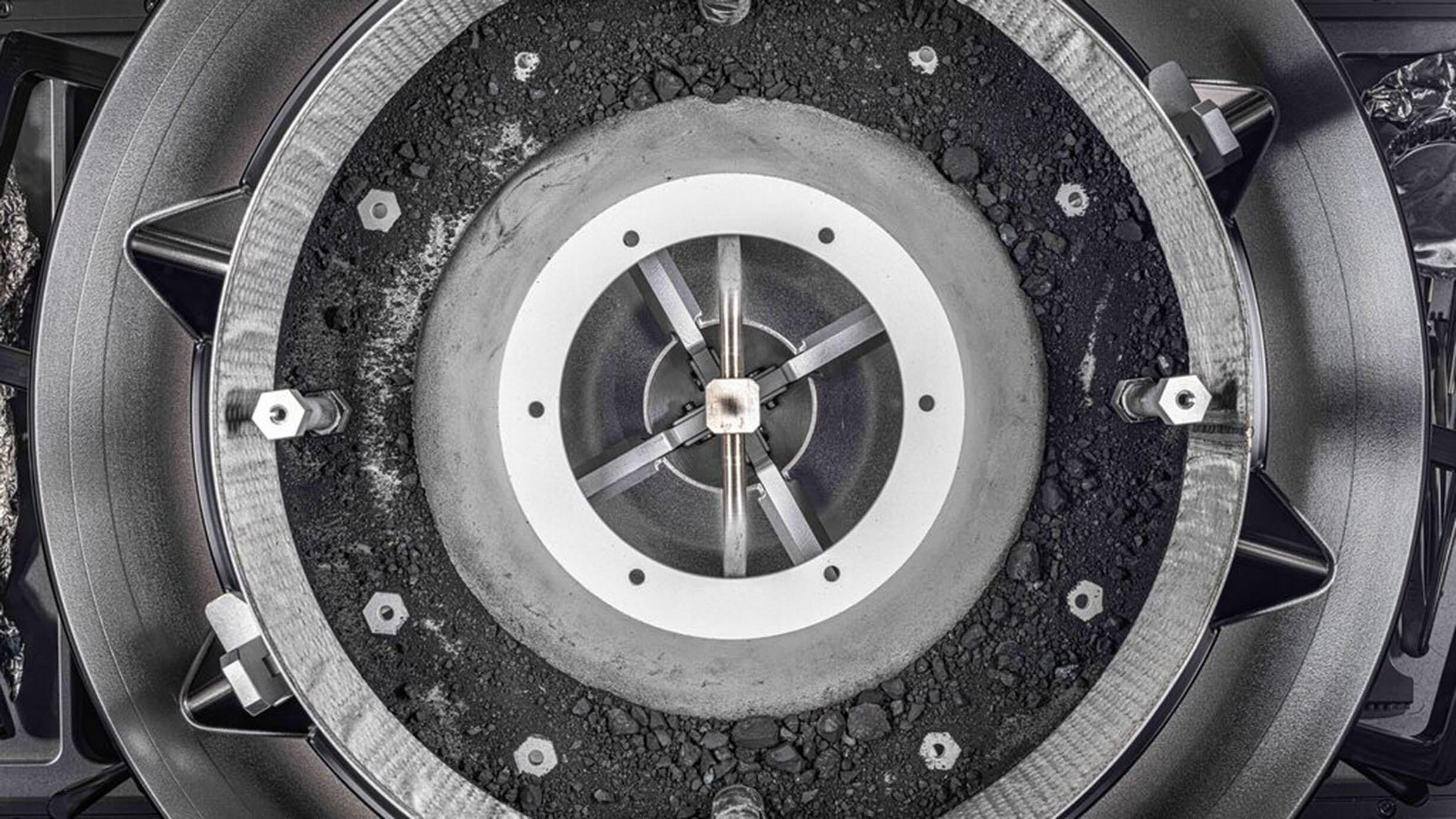 A large circular, metal container with samples of asteroid Bennu inside. 