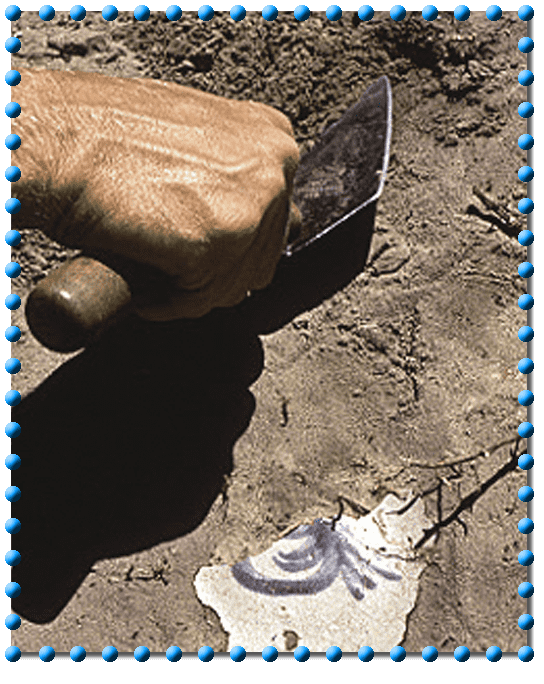 digging a piece of pottery up from the dirt with a trowel