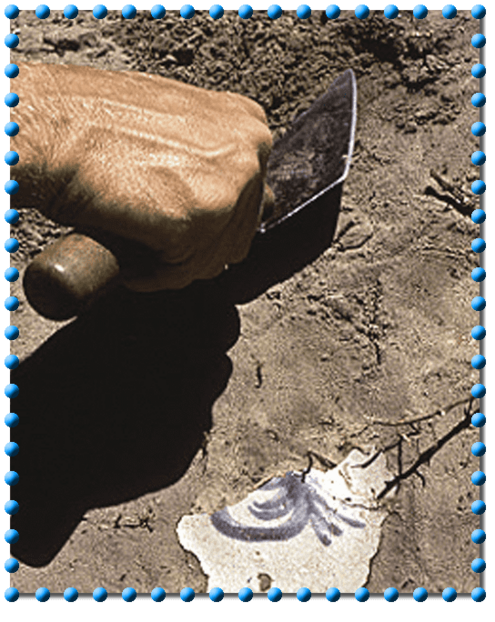 digging a piece of pottery up from the dirt with a trowel