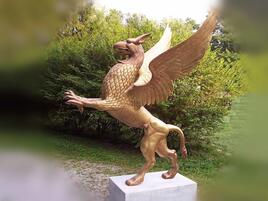 gold colored griffin statue in a park