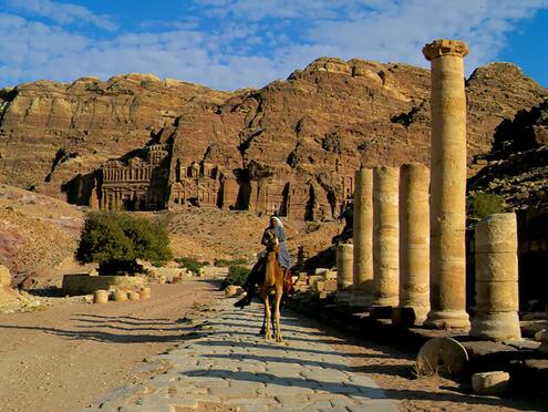 man riding camel down colonnaded street