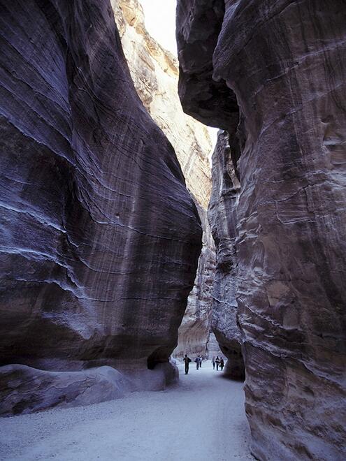 people walking through tall carved Siq