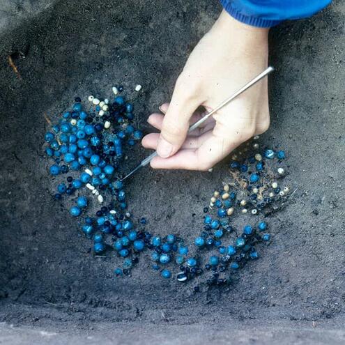 blue beaded necklace partially covered by dirt