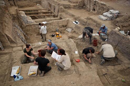 Ten people working to excavate the very large site of a former building.