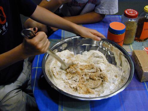 Closeup of a boy stirring cookie batter in a large metal bowl. 