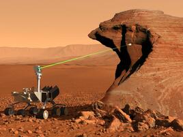 Curiosity rover (space rover with six wheels and a laser head) on a red rocky landscape. The laser is pointing a big rock.