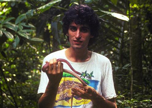 Chris holding a snake in the jungle.