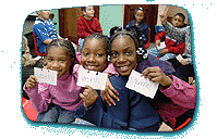Three children pose and hold up index cards which have different organism names written on them.