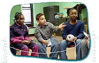 Three seated children hold a piece of string, with one child to the right holding the initial ball of twine from which the string is being pulled.