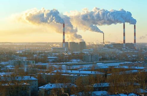 Four smokestacks spread across an urban environment. 