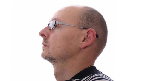 Profile of a bald man wearing glasses.