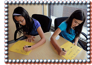 2 girls facing away from each other and each writing a note in marker on paper
