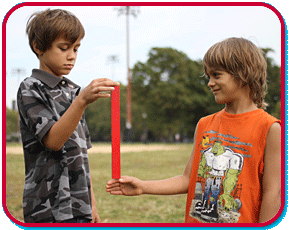 a boy holding a ruler, while a second boy has his hand below it waiting to catch the ruler