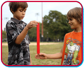 one boy holding a ruler from the top while a second boy has hand at the bottom waiting to catch it