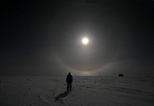 scientist walking at night across barren snowy land in Antarctica