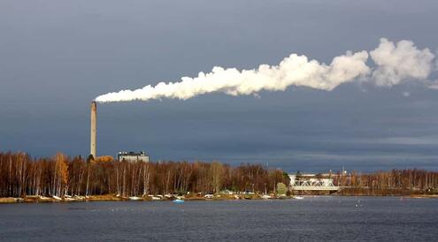 power plant near river's edge with billowing smoke stack