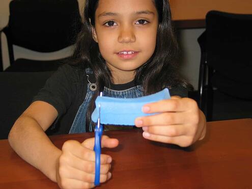 girl cutting off a piece of foam with a scissors