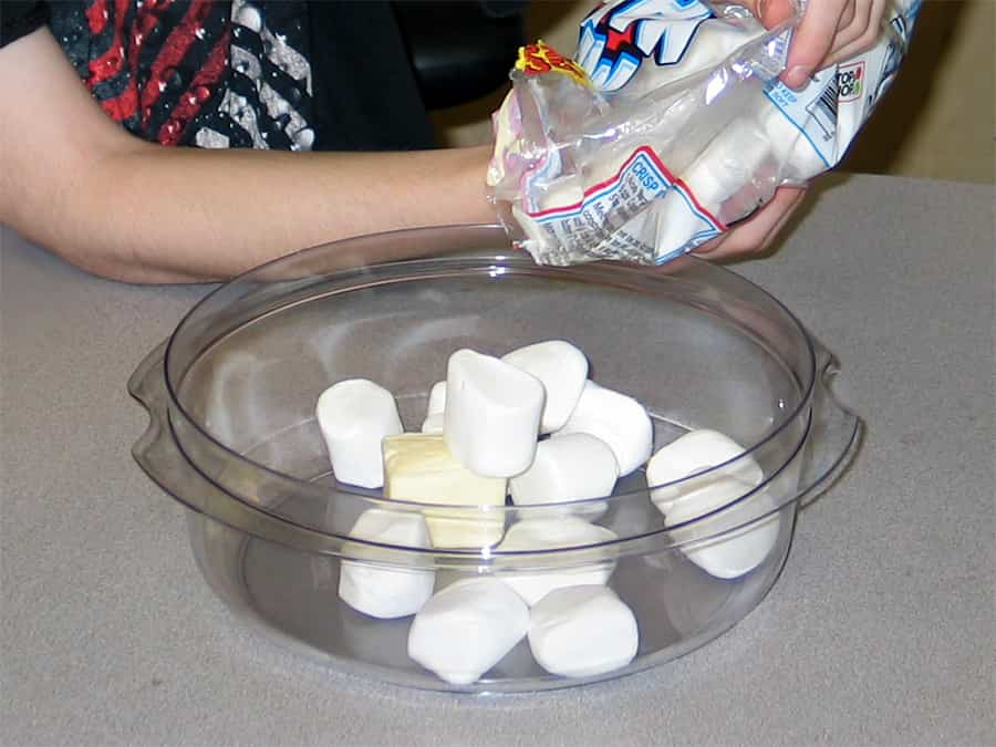dumping the butter and the marshmallows into the bowl