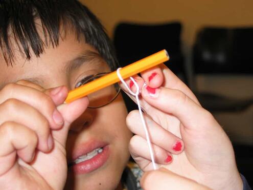 tying one end of the string to a pencil