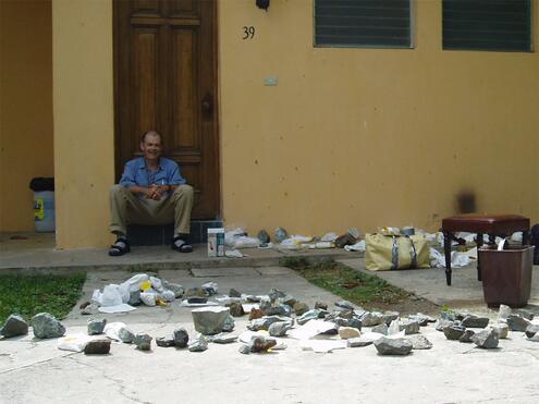 George Harlow sitting on patio with many raw jade samples spread out