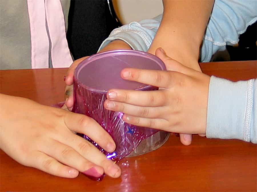 stretching plastic wrap over the can