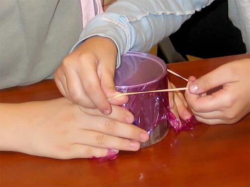 fitting the rubber band over the plastic wrap covering the can