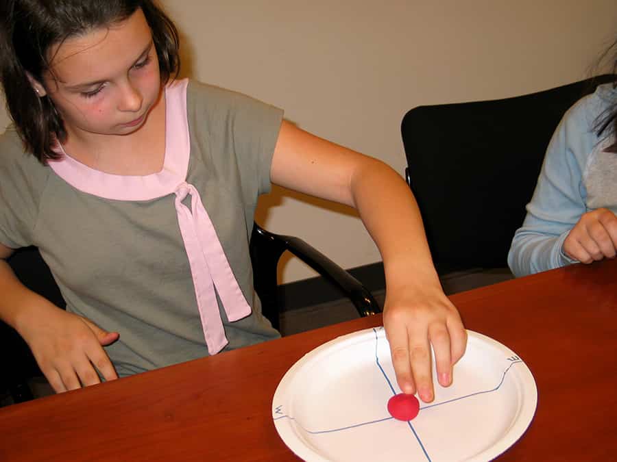 placing lump of model clay in center of paper plate