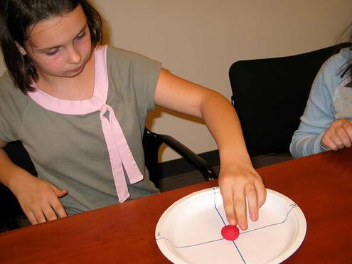 placing lump of model clay in center of paper plate