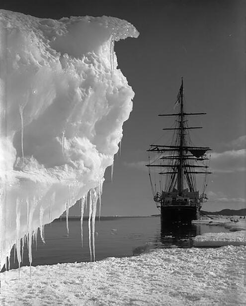 black and white photo of the ship pulled up to the ice shelf