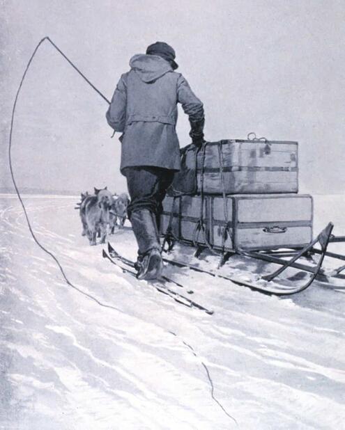 crew member walking next to dog-pulled sled piled up with suitcases 