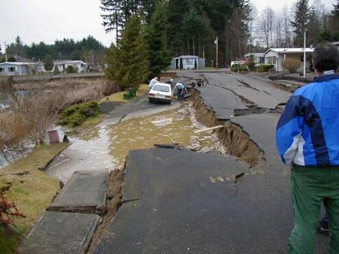 Deeply cracked road with car sliding off.