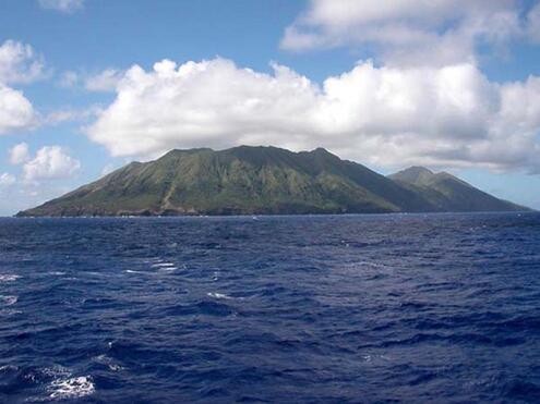 Ocean waves with volcanic island in background.