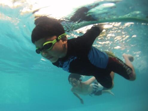 two boys swimming underwater with goggles on