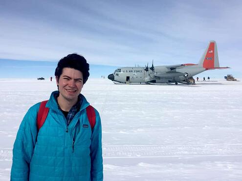Scientist Benjamin Keisling standing on snow with Air Force One plane in the background