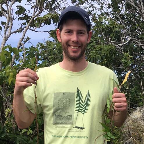 Scientist Donald McClelland holding plant specimens that he collected