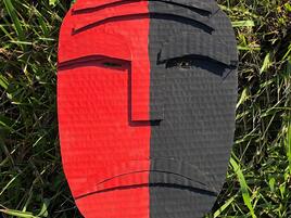 mask made of cardboard that is half red and half dark grey