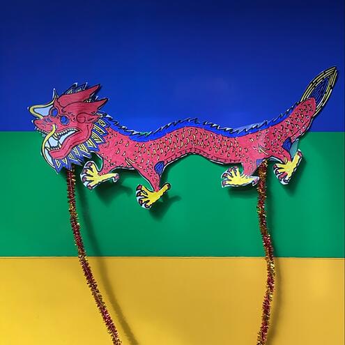illustrated puppet of red Asian dragon against colorful striped background
