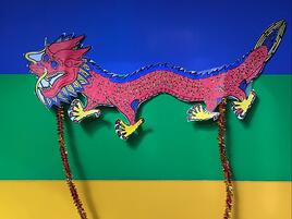 illustrated puppet of red Asian dragon against colorful striped background