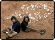 Mark Norell and Mike Novacek seated beside an unearthed fossil of an ankylosaur, pictured from above.