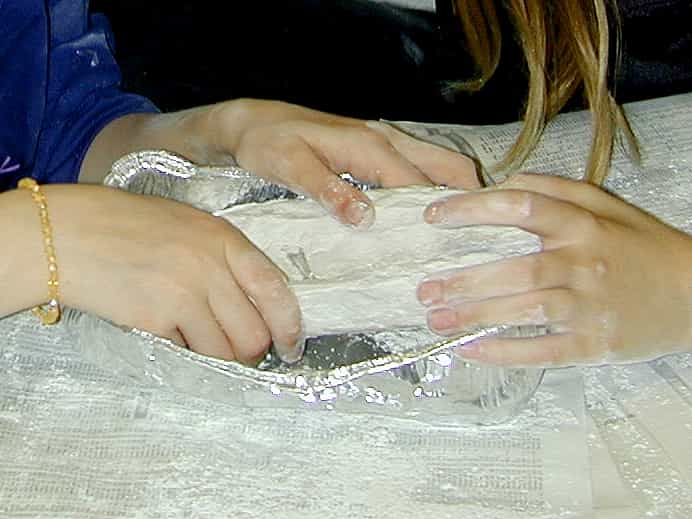 peeling away sides of aluminum container so plaster block pops out