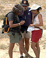 3 team members standing close together looking at a fossil