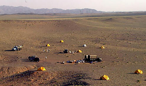 aerial view of a clearing with the team's trucks and yellow tents spread out