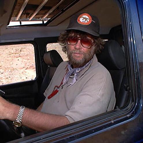 Mika Novacek behind the wheel of a jeep with cap and sunglasses on