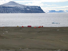 Group of tents by the water with floating ice and hills one the second term