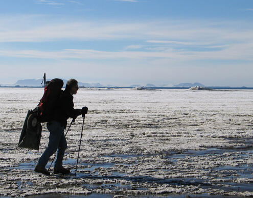Ross with hiking poles and a backpack hikes on flat snowy surface