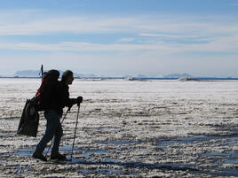 Ross with hiking poles and a backpack hikes on flat snowy surface