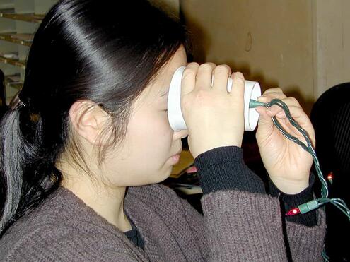 placing the cup with the holiday light in it over the person's eye