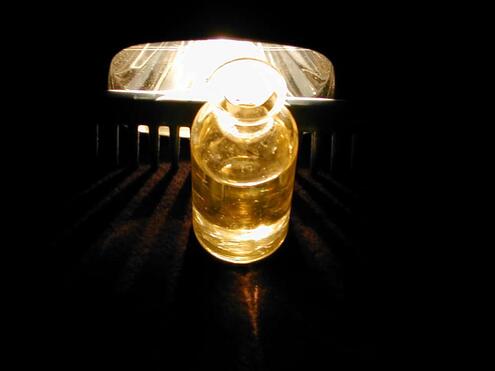 a glass jar with water in front of the light beams coming through the gaps between teeth of comb
