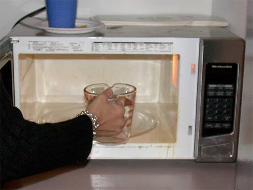 placing measuring cup of water into microwave