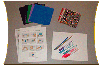 A flat surface with art supplies including colorful paper, pens and markers, and instruction sheets.